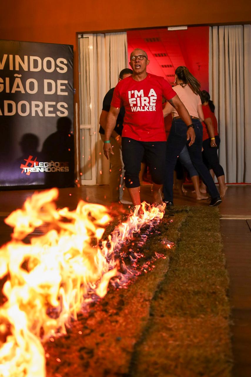 Homem caminhando sobre brasas em chamas usando camiseta vermelha I'm a Fire Walker