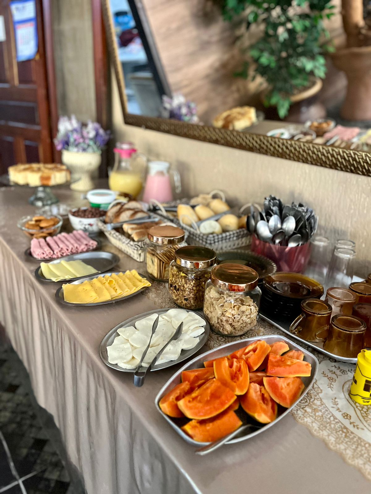 Mesa de café da manhã farta com frutas, pães, queijos e sucos