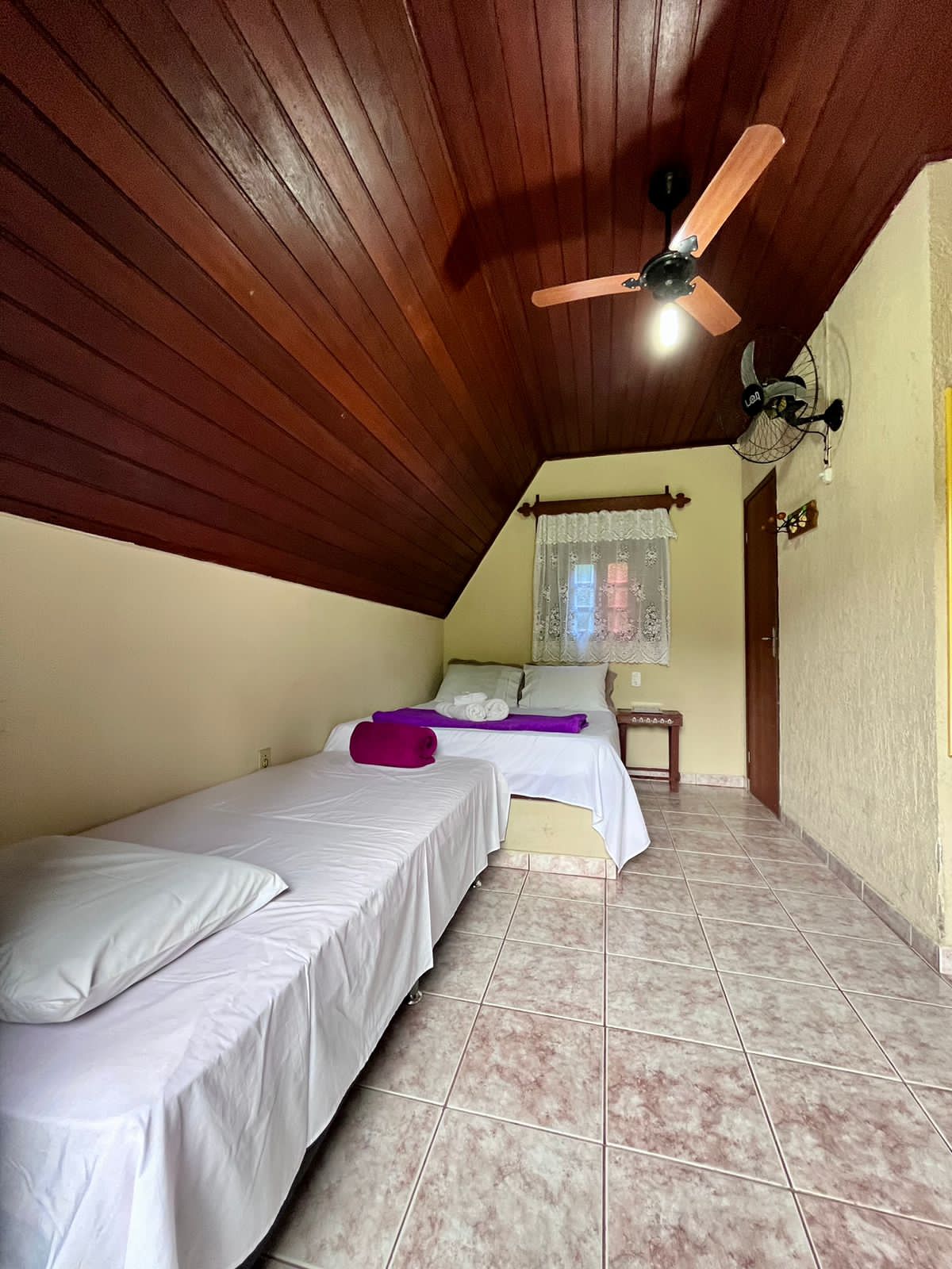 Quarto da Pousada Riacho Doce com camas arrumadas e teto de madeira